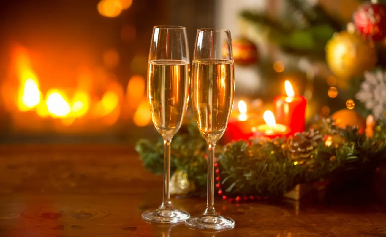 beautiful-new year-background-with-white wine-flutes-burning-fireplace-with-candles